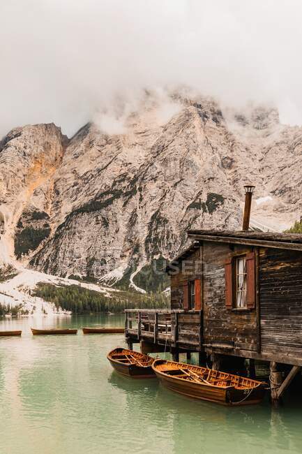 Increíble vista de la cordillera de los Dolomitas con el agua verde del lago que refleja pendientes rocosas ásperas cubiertas de niebla y nubes en Italia - foto de stock