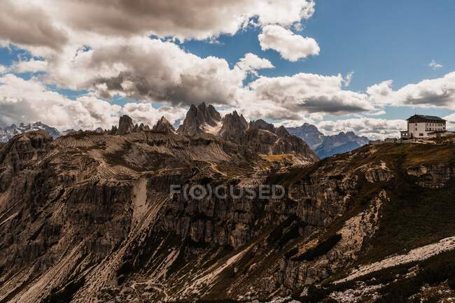 Espectacular paisaje de la cordillera Dolomita con ásperos picos rocosos bajo el cielo azul nublado a la luz del día en Italia - foto de stock