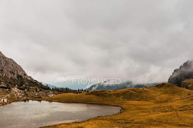 Von oben malerische Landschaft von kleinen See umgeben von Hügeln mit Nebel und Wolken in den Dolomiten Bergkette in Italien — Stockfoto