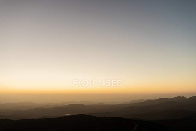Захід сонця над гірським хребтом на тлі безхмарного неба ввечері — стокове фото