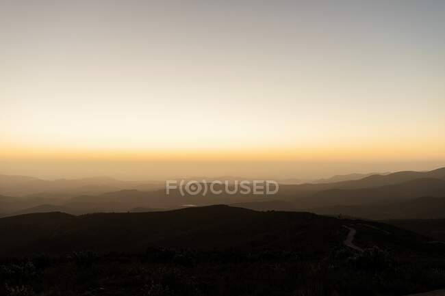 Sunset over mountain range on background of cloudless sky in the evening — Stock Photo