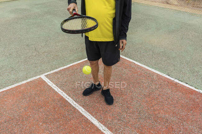 Ernte Senior Sportler Prellen Ball auf Schläger während der Vorbereitung für Tennis-Match auf dem Platz — Stockfoto