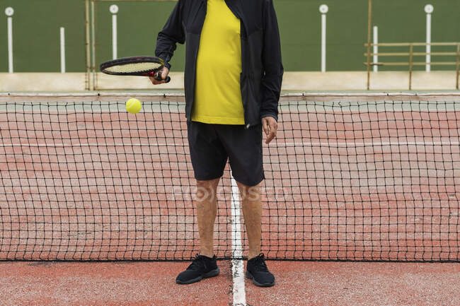 Crop senior sportivo palla rimbalzante sulla racchetta mentre si prepara per la partita di tennis in campo — Foto stock