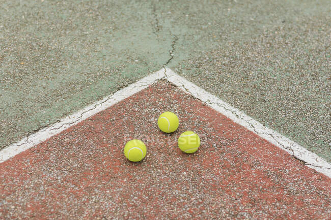 Von oben gelbe Bälle, die beim Training auf dem rissigen Boden des Tennisplatzes platziert wurden — Stockfoto