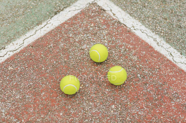 Сверху желтые мячи помещены на треснувшую площадку теннисного корта во время тренировки — стоковое фото