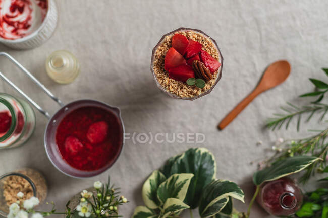 Верхний вид композиции стекла вкусный свежий ягодный напиток, украшенный нарезанной клубникой и орехами подается на стол — стоковое фото