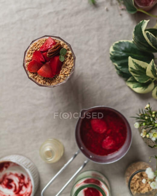 Top view composition of glass of delicious fresh berry drink garnished with cut strawberries and nuts served on table — Stock Photo