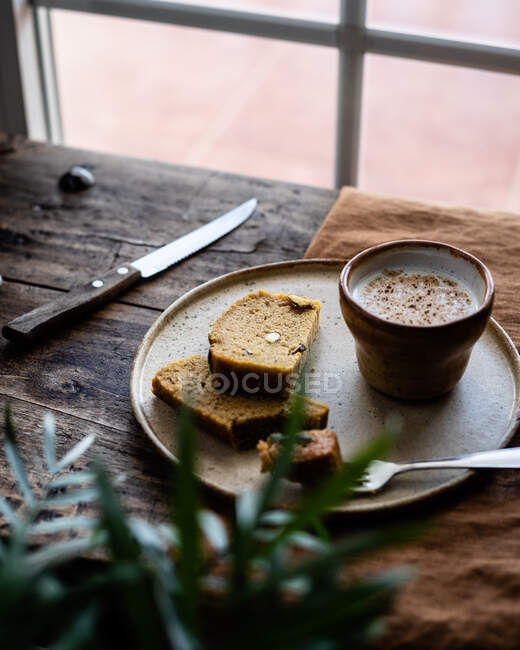 Composición de rebanadas de sabroso pan integral fresco servido en el plato con taza de leche fresca - foto de stock