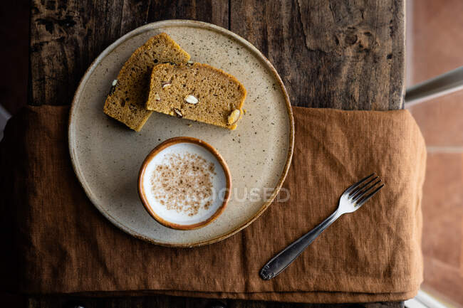 Top view composition of slices of tasty fresh wholegrain loaf served on plate with cup of fresh milk — Stock Photo