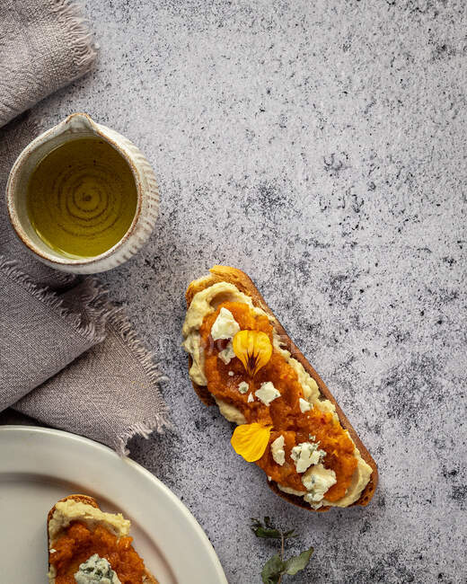 Toasts frais appétissants avec confiture et fromage de chèvre servis sur des assiettes et une table en marbre — Photo de stock
