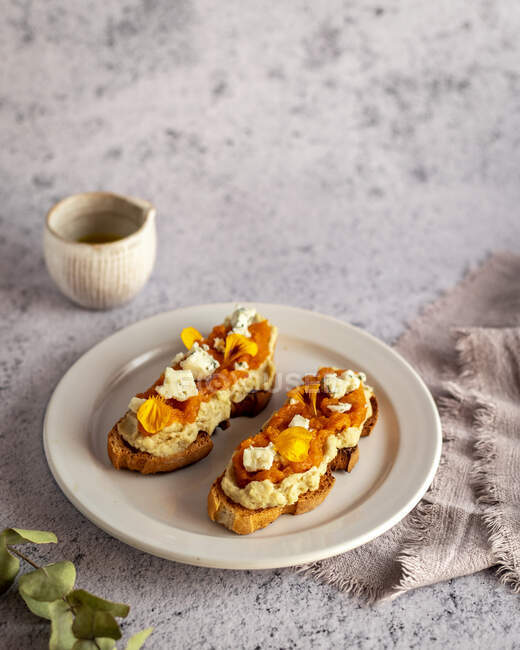 Dall'alto appetitosi toast freschi con marmellata e formaggio di capra serviti sul piatto vicino alla brocca con olio d'oliva biologico — Foto stock