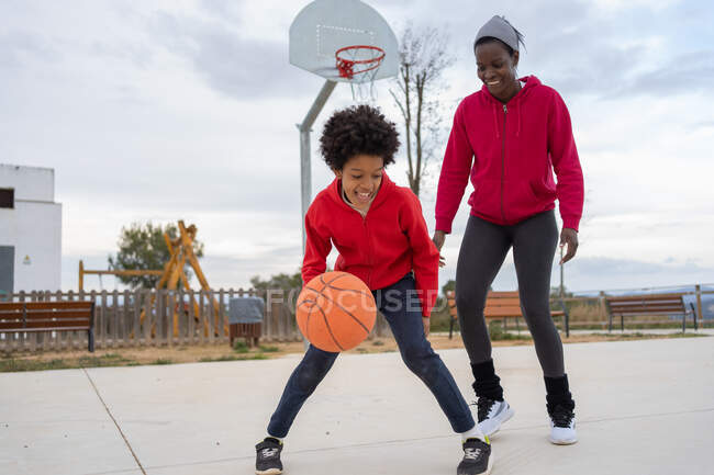 Африканская мать и сын играют в баскетбол на открытой баскетбольной площадке — стоковое фото