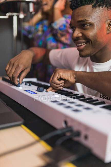 Vista lateral de los jóvenes socios afroamericanos utilizando netbook con software de grabación de sonido en la pantalla en el estudio de música - foto de stock