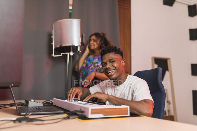 Побочный обзор молодых афроамериканских партнеров, использующих нетбук с программным обеспечением звукозаписи на экране в музыкальной студии — стоковое фото