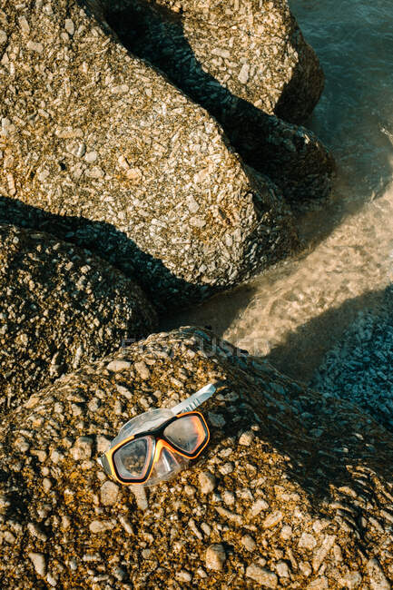 Primer plano de unas gafas de buceo sobre unas rocas en la playa - foto de stock