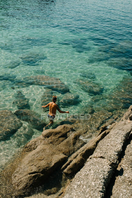 Homme marchant le long des rochers sur le bord de la mer — Photo de stock