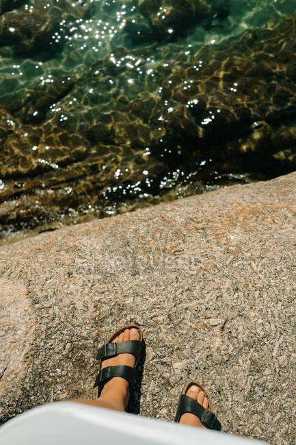 Close-up of women's sandals on some rocks and the sea below — Stock Photo
