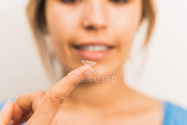 Урожай розмитий усміхнений жінка готується до контакту лінзи на кінчику пальця в світлій кімнаті — стокове фото