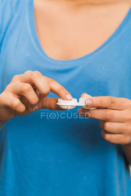 Crop faceless female in blue shirt holding reusable plastic pack of modern contact — Stock Photo