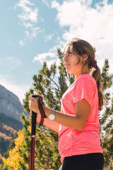 Вид сбоку на женский турист с палками, стоящими в Национальном парке Ordesa y Monte Perdido и наслаждающимися отдыхом в горах Пиренеев в солнечный день — стоковое фото