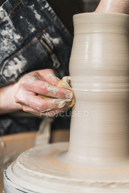 Cropped unrecognizable female artisan creating clay tableware on pottery wheel while working in art studio — Stock Photo