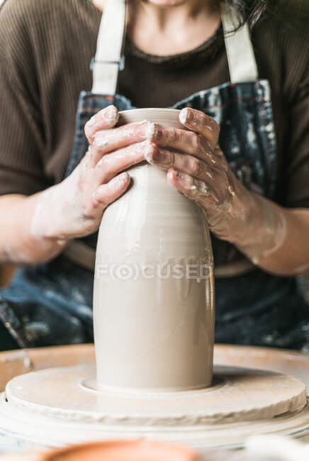 Обрізана невпізнавана жінка-художниця створює глиняний посуд на керамічному колесі під час роботи в художній студії — стокове фото