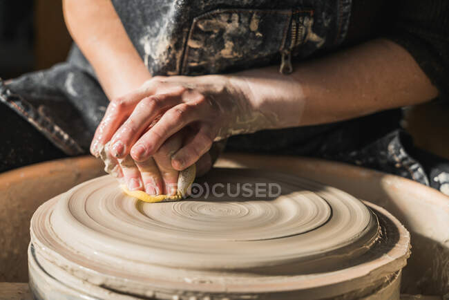 Обрізати невпізнаваних майстрів, створюючи глиняний посуд на гончарному колесі в студії — стокове фото