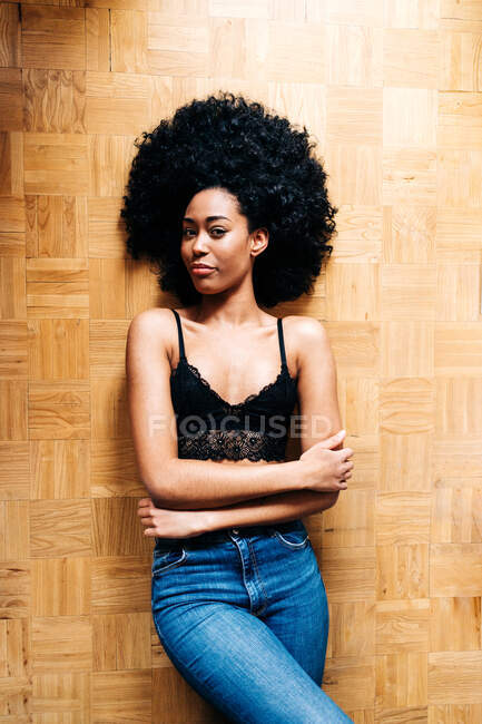 Von oben eine schlanke Afroamerikanerin mit lockigem Haar, die auf dem Parkettboden liegt und in die Kamera blickt — Stockfoto
