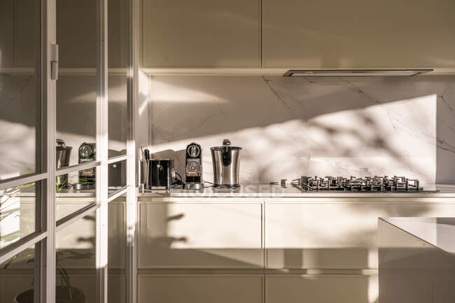 Інтер'єр сучасної домашньої кухні зі світлими меблями і дзеркальними елементами в денне світло — стокове фото