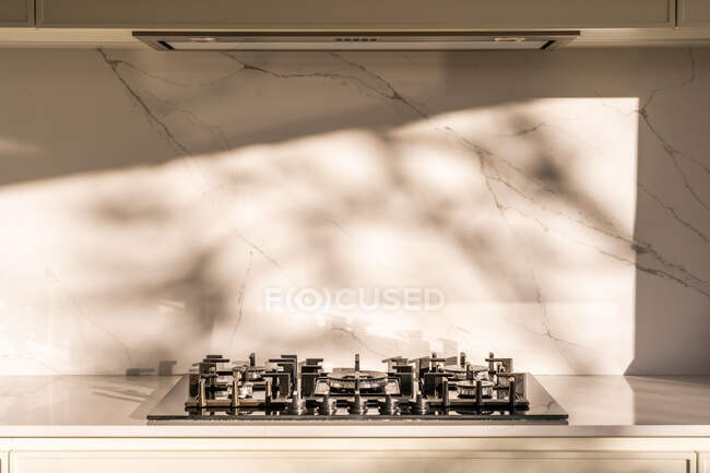 Table de cuisson moderne au gaz inoxydable et hotte dans la cuisine maison légère avec mur en marbre — Photo de stock