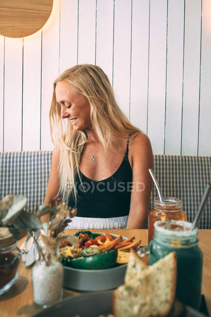 Mulher loira olhando para o lado sentado em um restaurante — Fotografia de Stock
