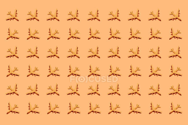 Верхний вид орнамента пластиковых игрушечных самолетов, расположенных рядами на оранжевом фоне — стоковое фото