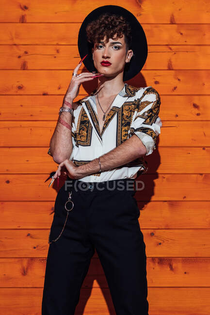 Young transgender man in trendy wear with red lips looking at camera in cabin — Stock Photo