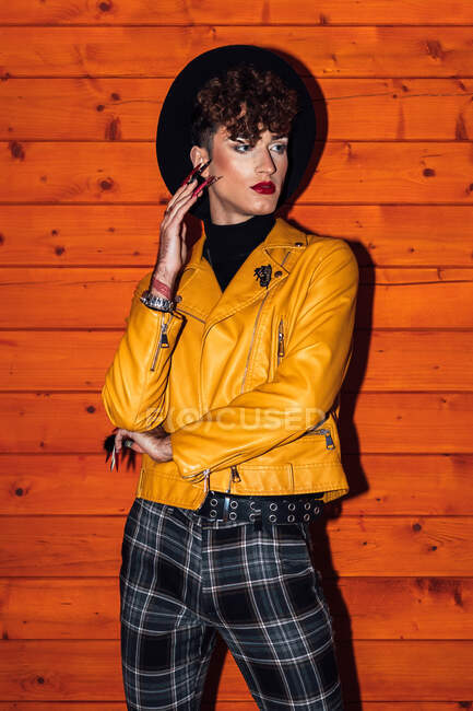 Молодой трансгендер в модной одежде с красными губами, смотрящий в каюту — стоковое фото