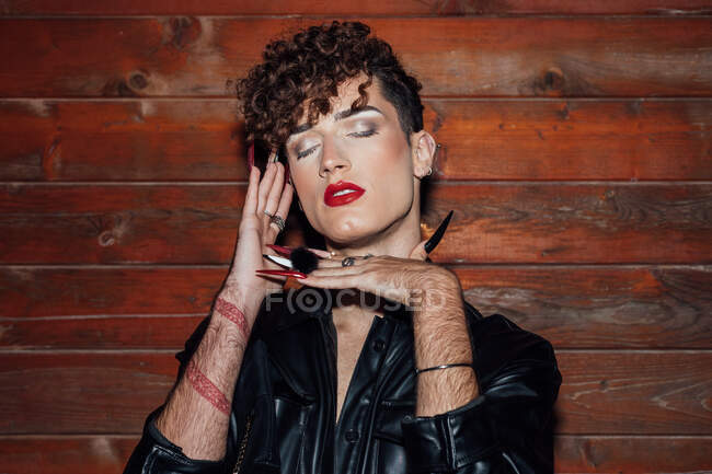 Jovem transexual na moda masculino com unhas compridas e olhos fechados contra a parede de madeira em chalé — Fotografia de Stock