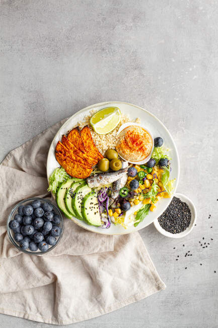 Top view of plates with delicious fresh apple and lime slices near sweet potato wedges and olives with hummus on table — Stock Photo