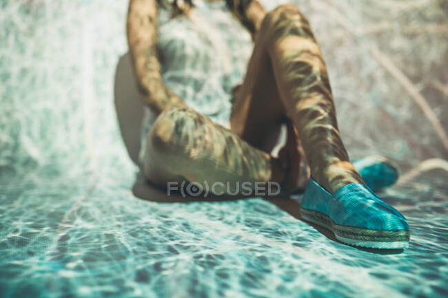 Анонімні жінки в літніх туфлях сидять під абстрактним проектуванням заплутаних білих ліній. — стокове фото