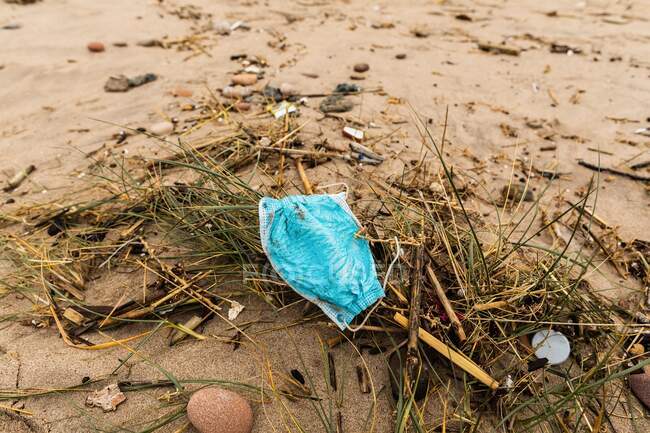 High angle of used dirty protective mask on sandy shore showing concept of environmental pollution — Stock Photo