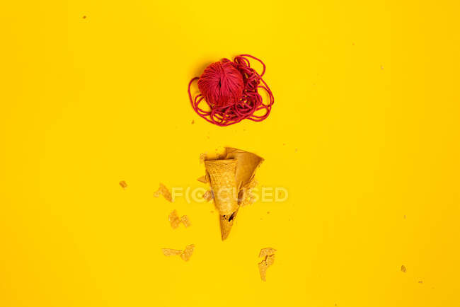 Vista dall'alto del cono di cialda rotto sotto la palla di filo rosso di lana che rappresenta il gelato — Foto stock