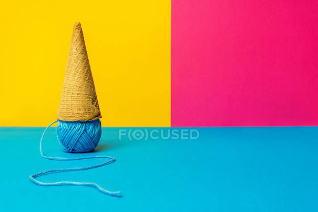 Bola de hilo de lana debajo del cono de gofre que representa gelato sobre fondo colorido - foto de stock