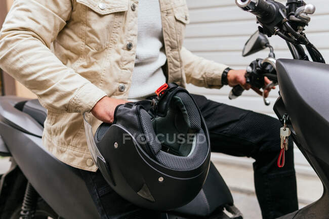 Side view of crop unrecognizable masculine male motorcyclist with helmet on motorbike in town — Stock Photo