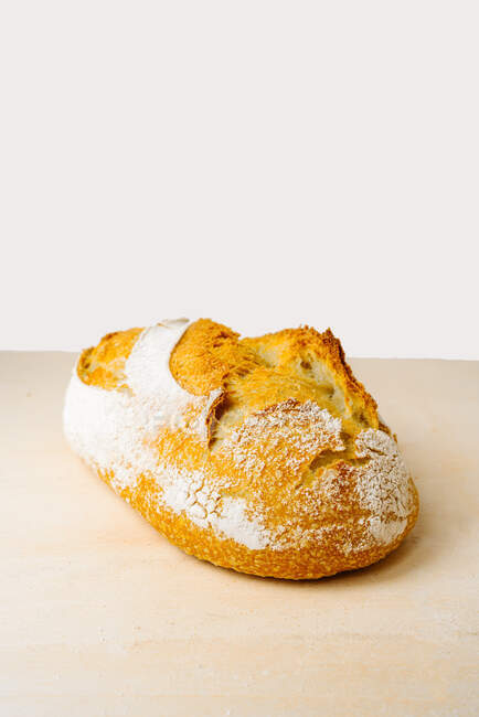 Leckeres Brot mit Mehl auf goldener Oberfläche in der Bäckerei auf weißem Hintergrund — Stockfoto