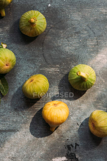 Higos verdes dulces maduros, recién cosechados del árbol doméstico, sobre una mesa con textura grunge. También conocido como higos blancos maduros - foto de stock