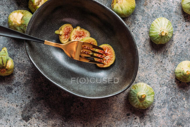 Зеленый инжир ломтики в современной черной миске на столе с гранж текстурой. минимальная концепция питания. Также известный как спелые белые инжиры — стоковое фото