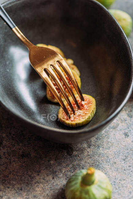 Зелені скибочки інжиру в сучасній чорній мисці на столі з гранжевою текстурою. мінімальна концепція їжі. Також відомі як стиглі білі інжир — стокове фото