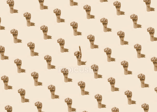 Von oben das Muster hölzerner Hände mit geballten Fäusten und einer mit Zeigefinger, der nach oben zeigt auf beigem Hintergrund — Stockfoto