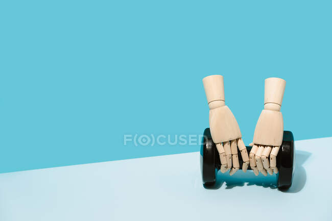 Creative wooden hands holding dumbbell in studio on light blue background showing concept of sports and workout — Stock Photo