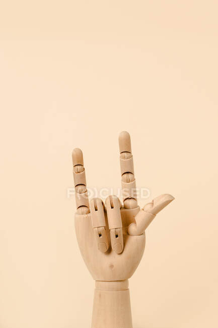 Mano creativa in legno che mostra il gesto del rock and roll su sfondo beige in studio — Foto stock