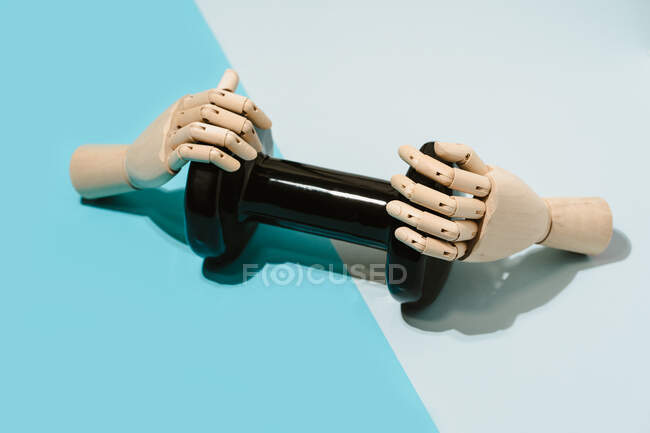From above creative wooden hands holding dumbbell in studio on light blue background showing concept of sports and workout — Stock Photo