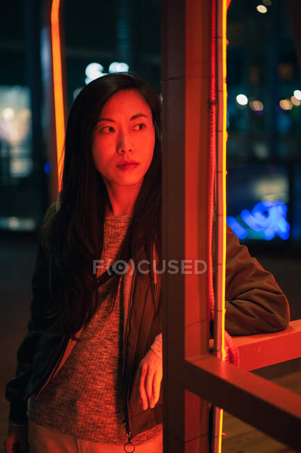 Porträt eines asiatischen Mädchens, das nachts in der Nähe von Neonlicht auf der Straße steht — Stockfoto